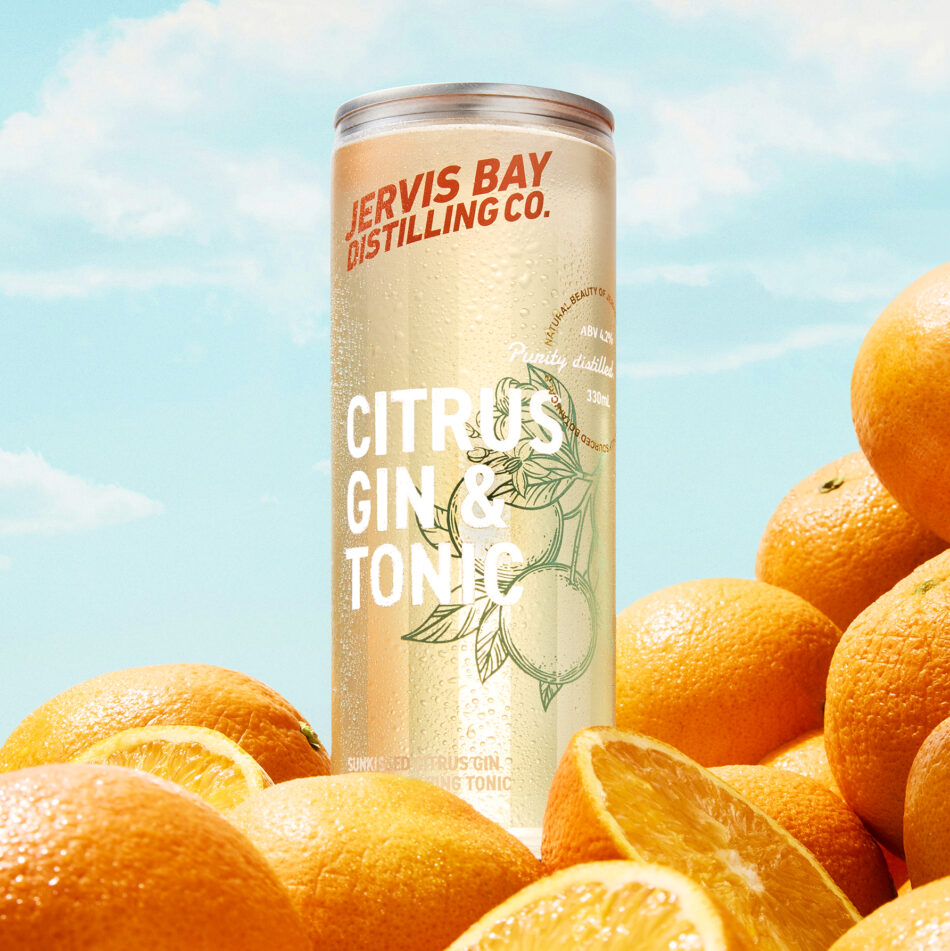 Jervis Bay Distilling Co. Citrus Gin & Tonic RTD can with fresh oranges in the sun